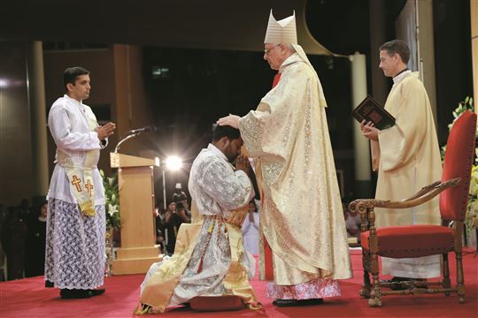  Bischof Hinder weiht einen jungen Mann zum Priester.
