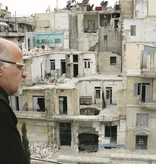 Pater Bassam Zaza schaut auf die Trümmer eines Stadtviertels in Aleppo.