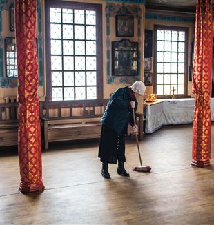 Eine Frau fegt den Boden in der Nikolaus-Kirche von Artemiwsk.